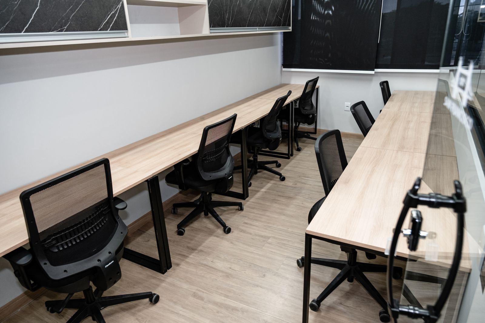 Interior de sala privativa do Enjoy Work com bancadas de madeira e cadeiras ergonômicas